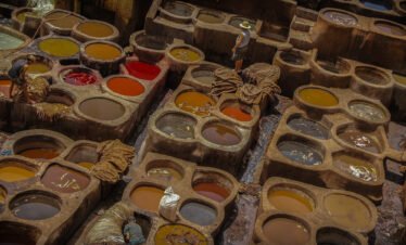 Hidden riad courtyard discovered during a Medina Secrets tour Tourists exploring narrow alleys of Marrakech medina with guide Traditional Moroccan tiles and fountain in a secret medina garden Local artisan crafting leather goods in a Marrakech souk Interior of a restored caravanserai in the old medina Guide explaining medina history in front of ancient wooden door Colorful spice market in the heart of the medina View of hidden rooftop terrace overlooking Marrakech medina morocco travel bliss