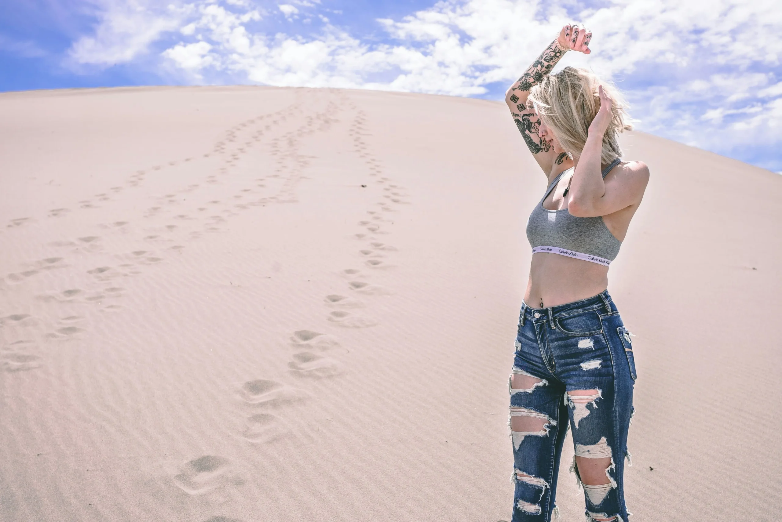 Footprints on the Golden Dunes of Merzouga Desert, Morocco Footprints leading across the soft sand dunes under a bright blue sky in Merzouga