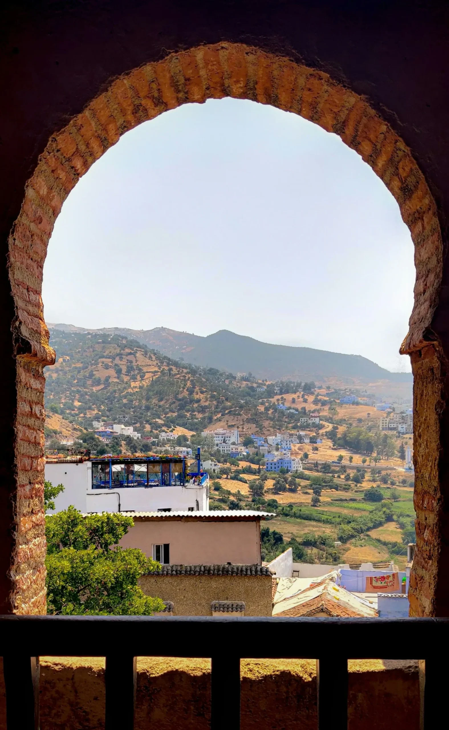View Over Chefchaouen from Ancient Window Scenic mountain view of Chefchaouen framed by a traditional Moroccan archway